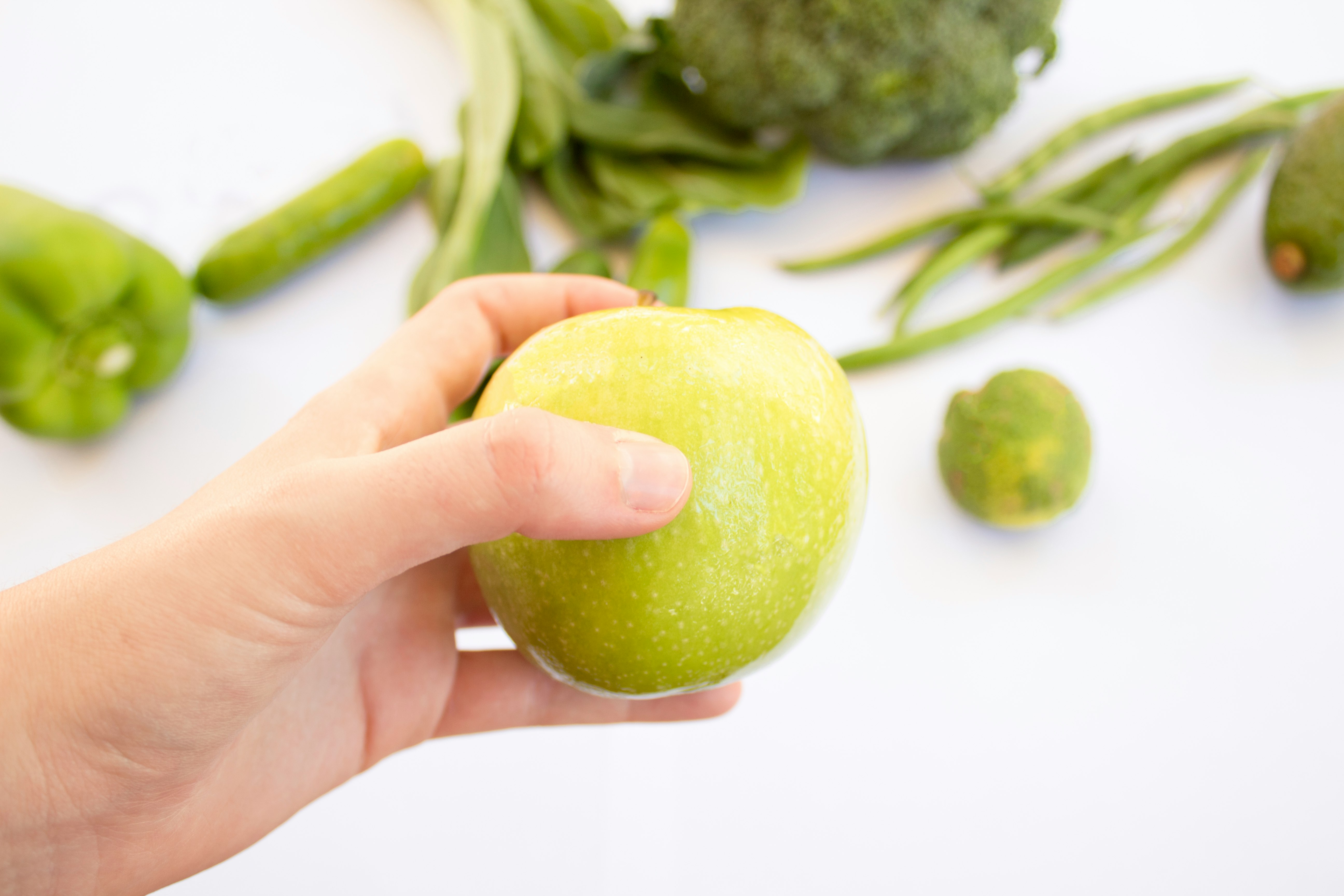 person's hand holding green apple